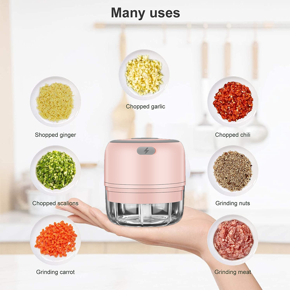 Ein rosa Küchenmaschine auf einer Hand, umgeben von Tellern mit gehackten Zutaten: Knoblauch, Ingwer, Chili, Nüsse, Fleisch, Karotten und Schnittlauch.