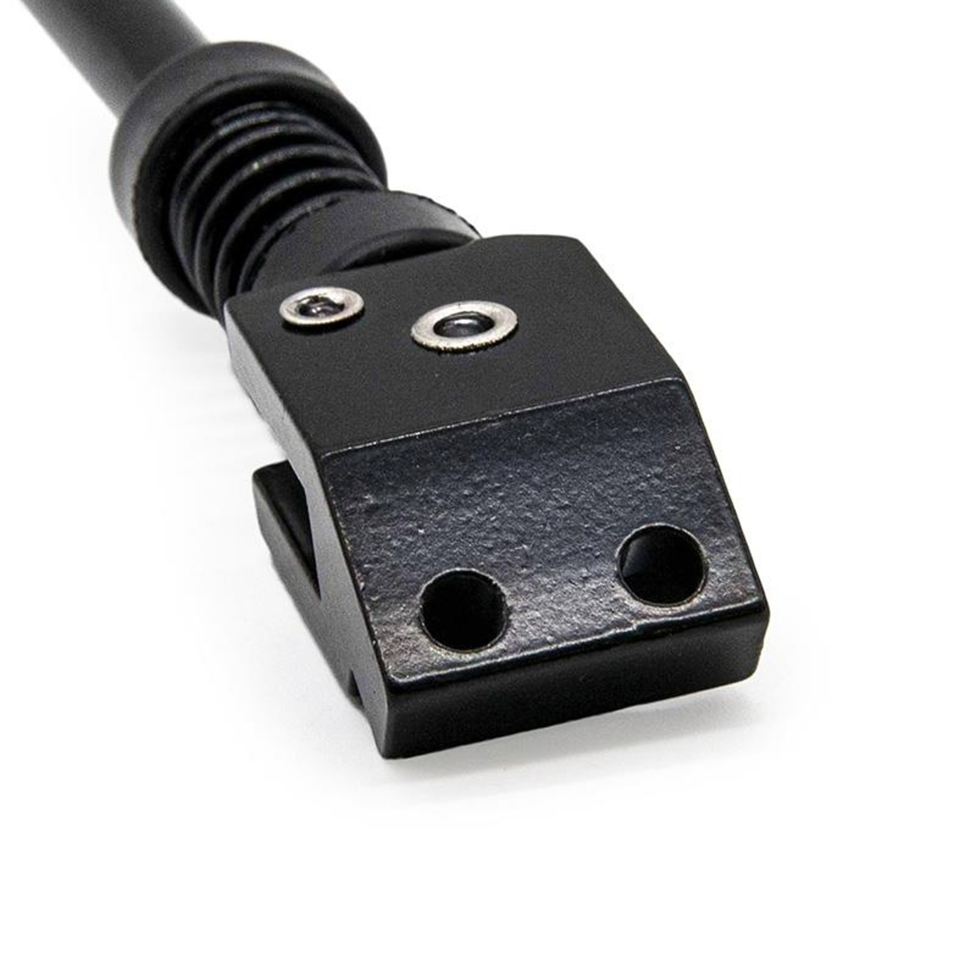 Primer plano de un componente metálico negro con dos agujeros. Está sobre un fondo blanco. La pieza está conectada a un tubo negro.