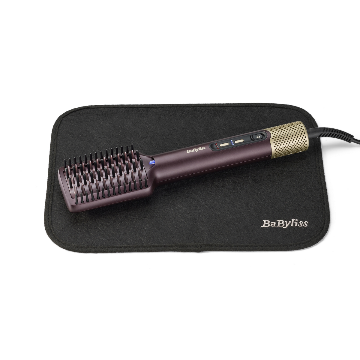 Eine BaByliss-Haarbürste auf einer schwarzen Matte. Die Bürste ist lila und gold, mit einem schwarzen Kabel. Die Matte hat das BaByliss-Logo.