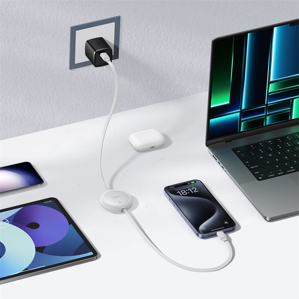 Ein weißer Schreibtisch, auf dem mehrere Geräte geladen werden. Ein Laptop, ein Telefon, ein Tablet und AirPods sind vorhanden. Ein Ladegerät ist an der Wand angeschlossen.