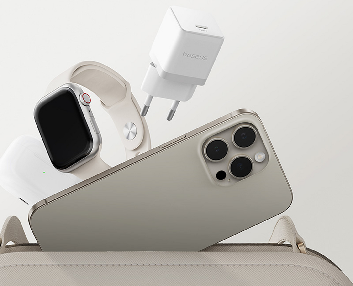 Un telefono, uno smartwatch, auricolari e un caricatore sono disposti vicino a una borsa. Il telefono è dorato, l'orologio e gli auricolari sono bianchi.