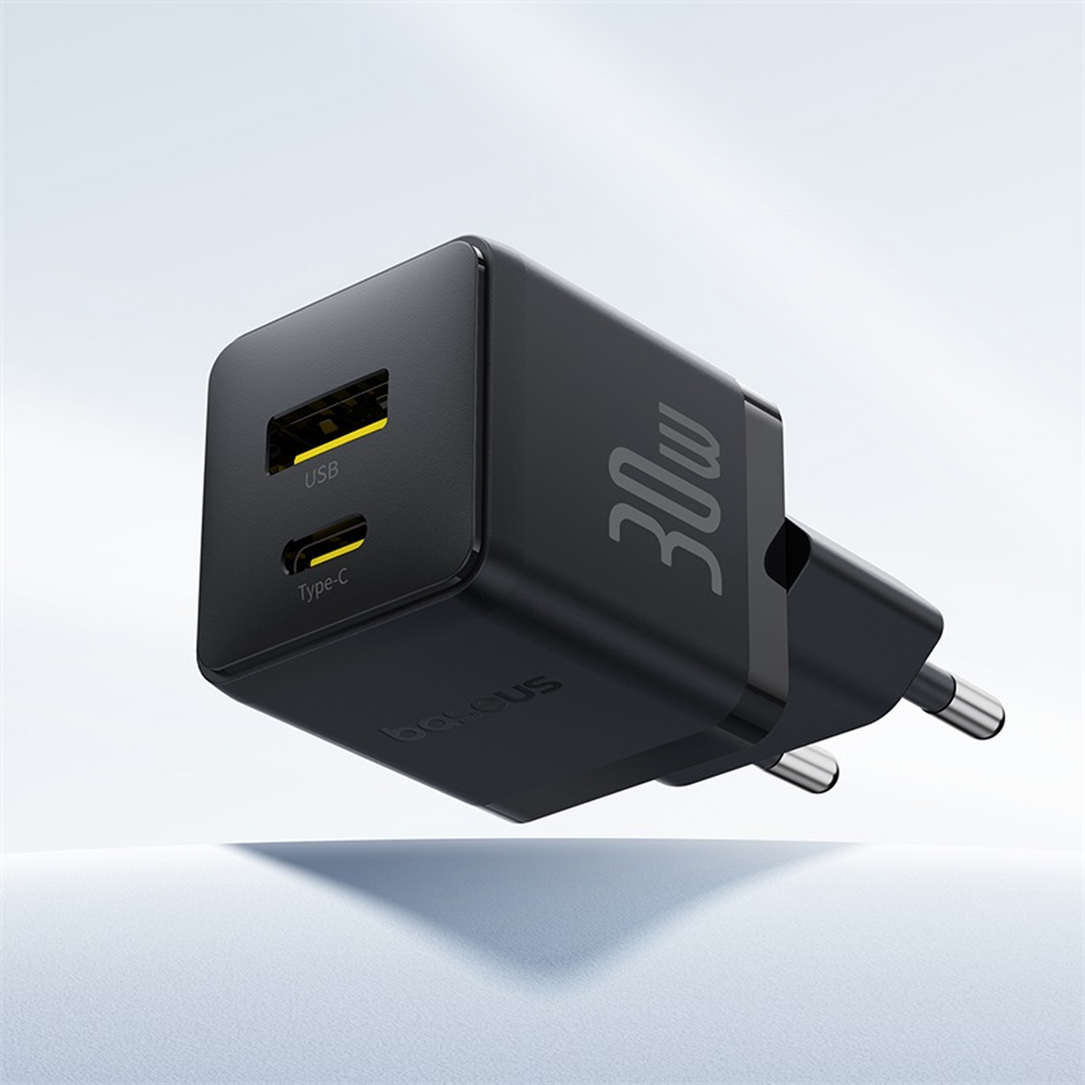 Un chargeur USB noir de 30W. Il possède des ports USB et Type-C, et une prise à deux broches. Le fond est blanc.