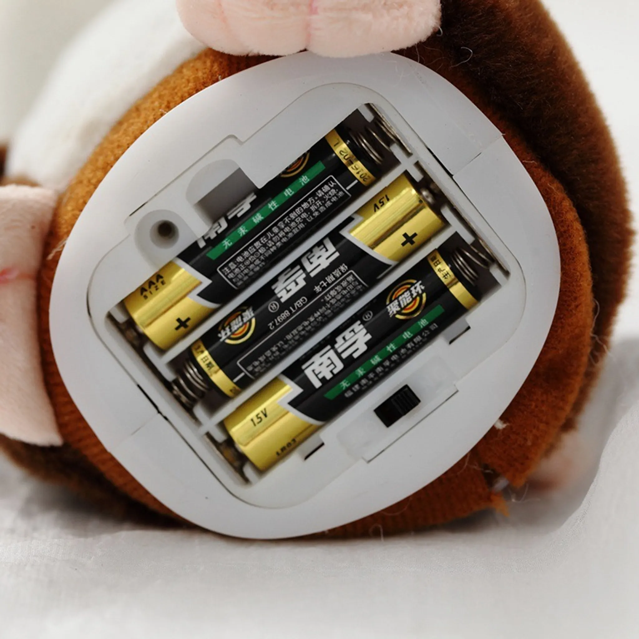 Das Batteriefach eines Spielzeugs enthält vier AA-Batterien. Die Batterien sind gold und schwarz. Das Spielzeug ist braun.