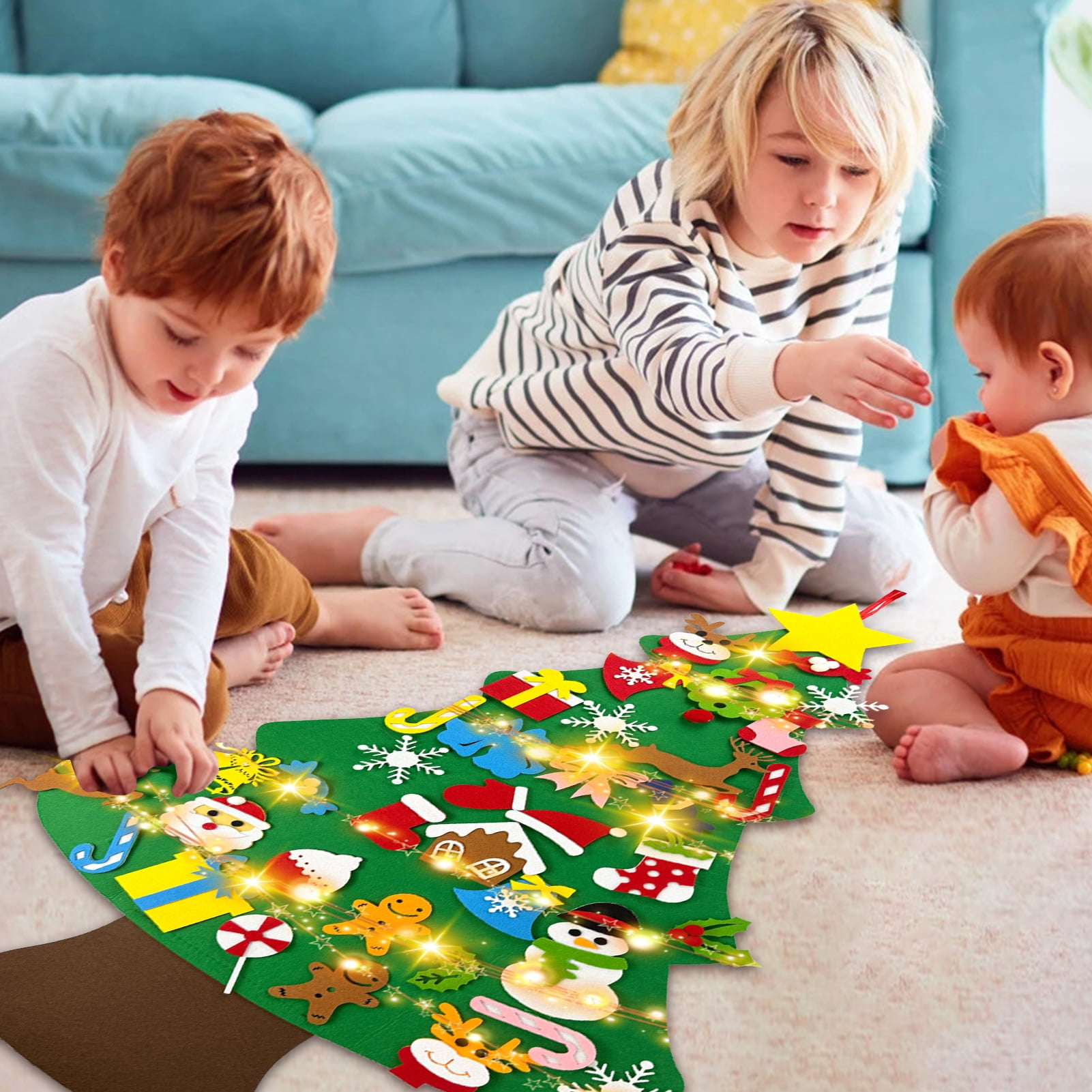 Drei Kinder um einen Weihnachtsbaum aus Filz mit Ornamenten. Ein Kind ist rothaarig, eines blond und eines ein Baby.