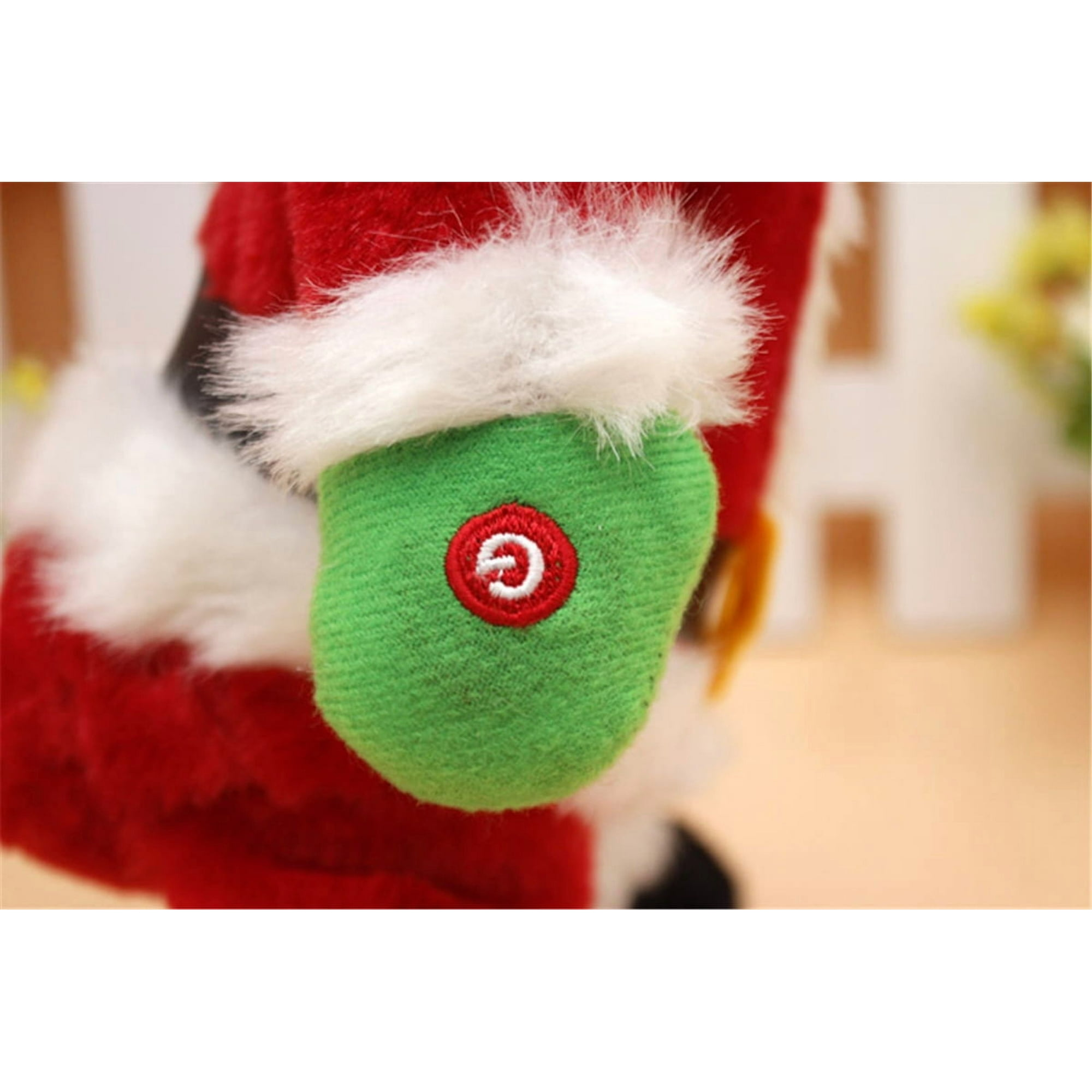Nahaufnahme des grünen Fäustlings eines Weihnachtsmann-Spielzeugs. Es hat einen roten Kreis mit einem weißen „G“-Symbol. Roter und weißer Pelzbesatz.