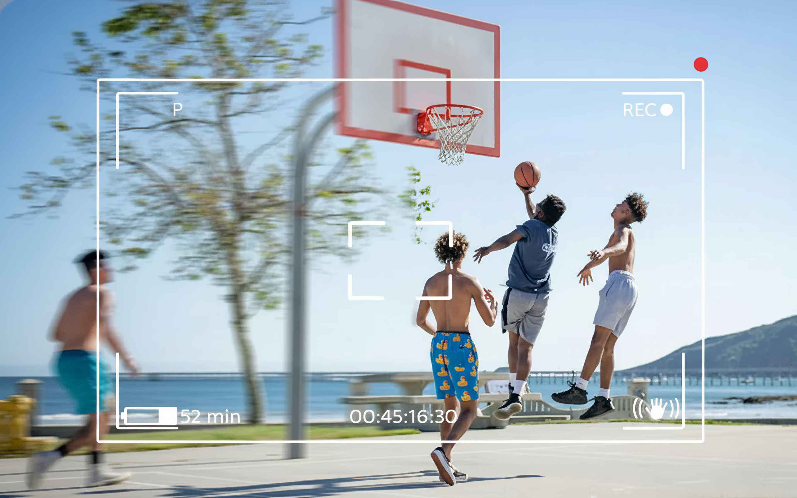 Drei Männer spielen Basketball auf einem Freiplatz. Einer springt zum Schießen, zwei andere schauen zu. Overlay auf dem Bild.