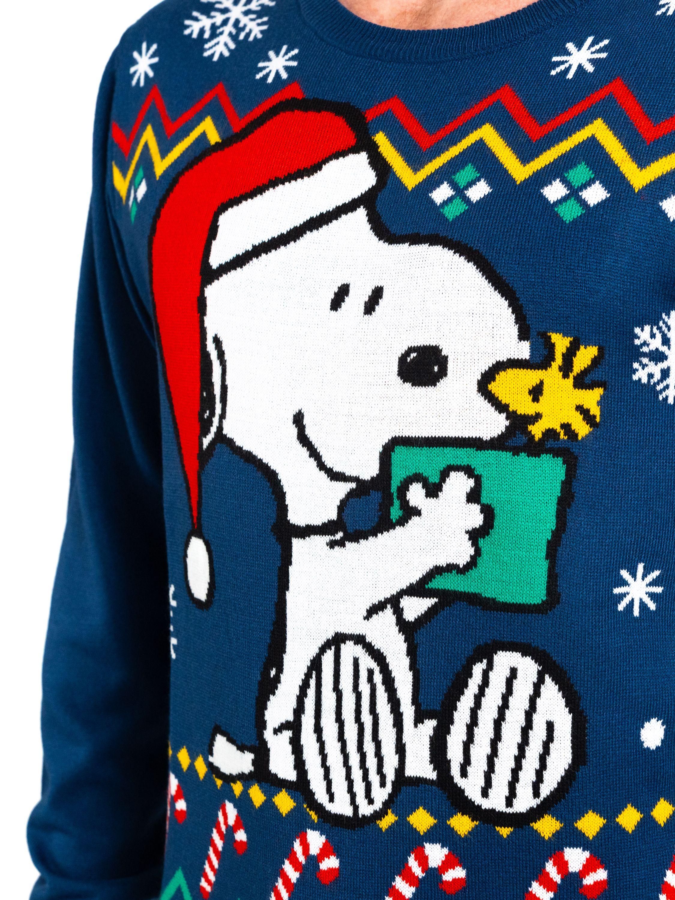 Dunkelblauer Weihnachtspullover mit Snoopy mit Weihnachtsmütze, der ein Geschenk hält, mit Schneeflocken und Zuckerstangen.