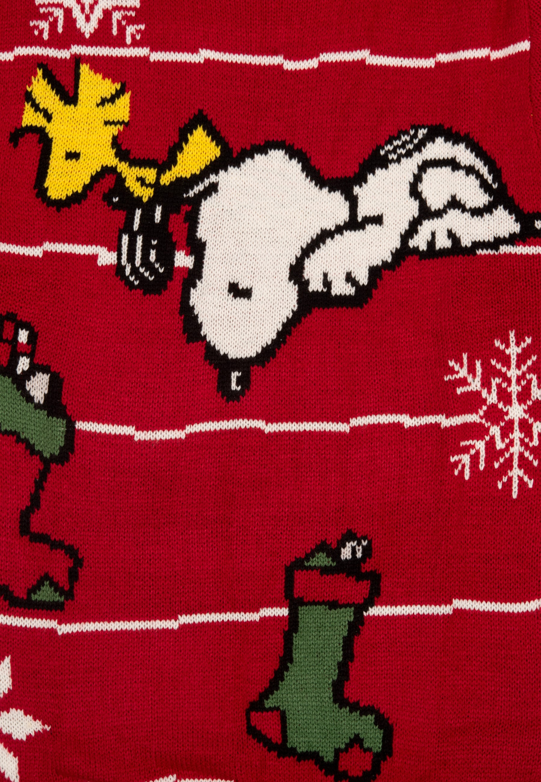 Ein roter Weihnachtspullover mit Snoopy- und Woodstock-Designs, weißen Streifen und Schneeflocken- und Strumpfdetails.