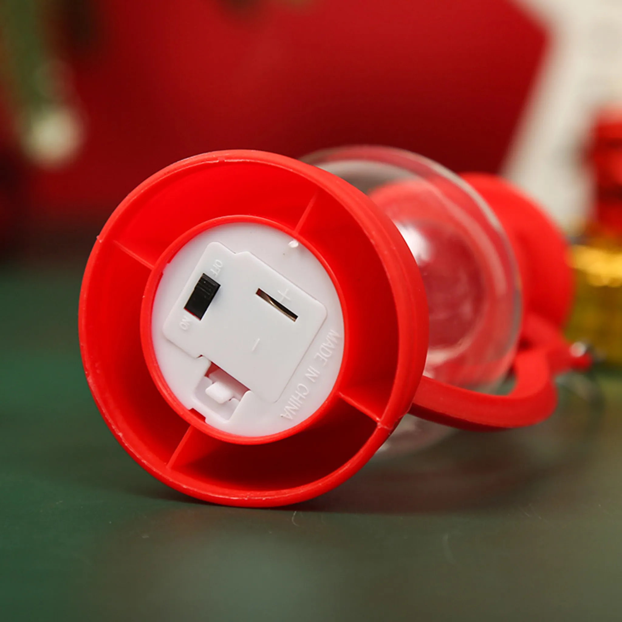 Roter Laternensockel, weißes Batteriefach und Ein-/Ausschalter. Klare Glaskugel, roter Griff. Hergestellt in China.