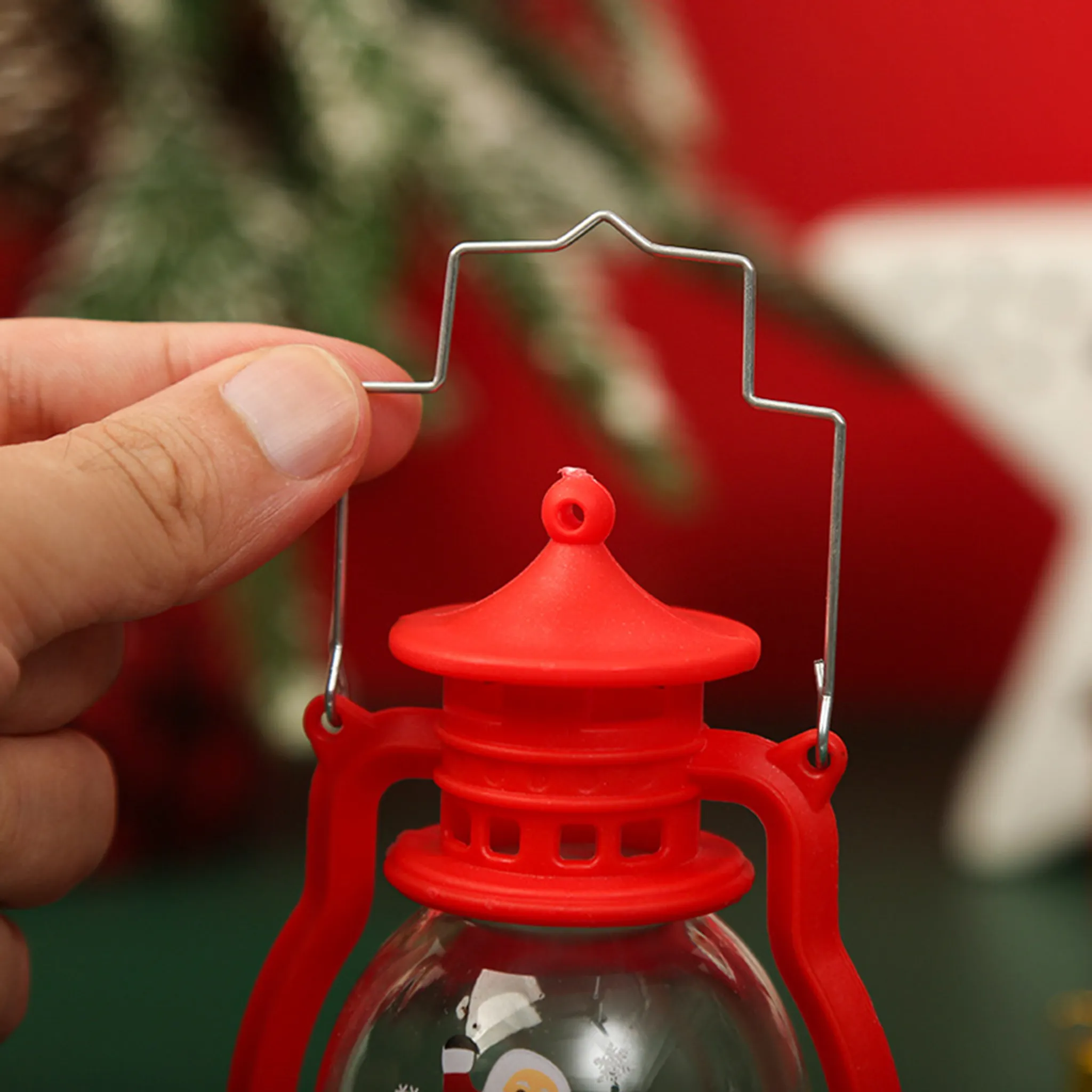 Eine Hand hält eine rote Laterne mit einem silbernen Griff. Der Hintergrund ist rot und grün, was auf Weihnachten hindeutet.