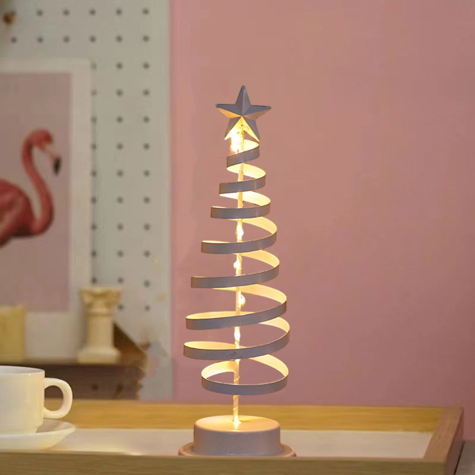 Ein dekoratives Licht in Form eines spiralförmigen Weihnachtsbaums mit einem Stern oben. Rosa Hintergrund.