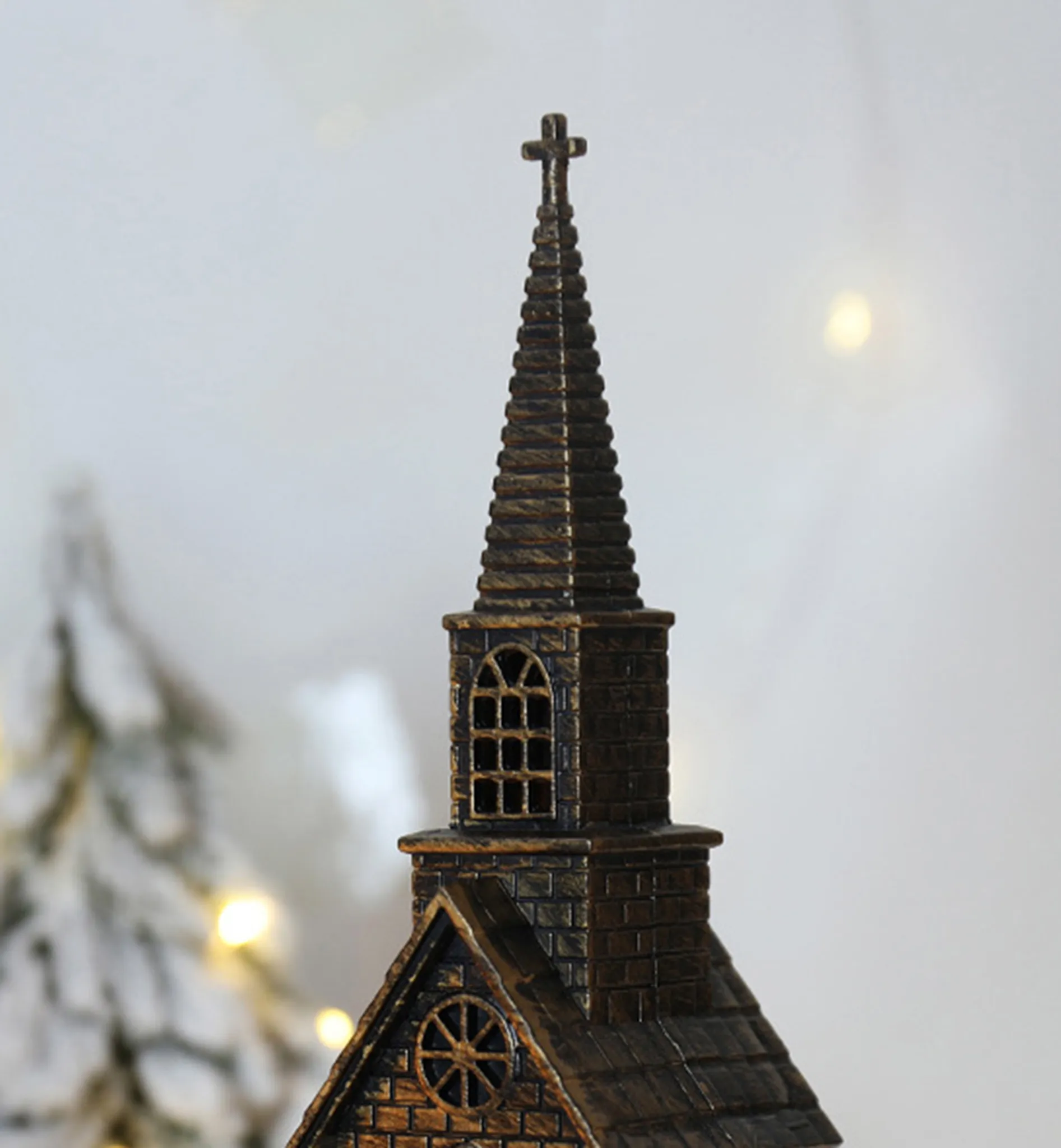 Eine dekorative Kirchenfigur mit einem Kreuz oben, Ziegeldetails und einem schneebedeckten Hintergrund mit sanften Lichtern.