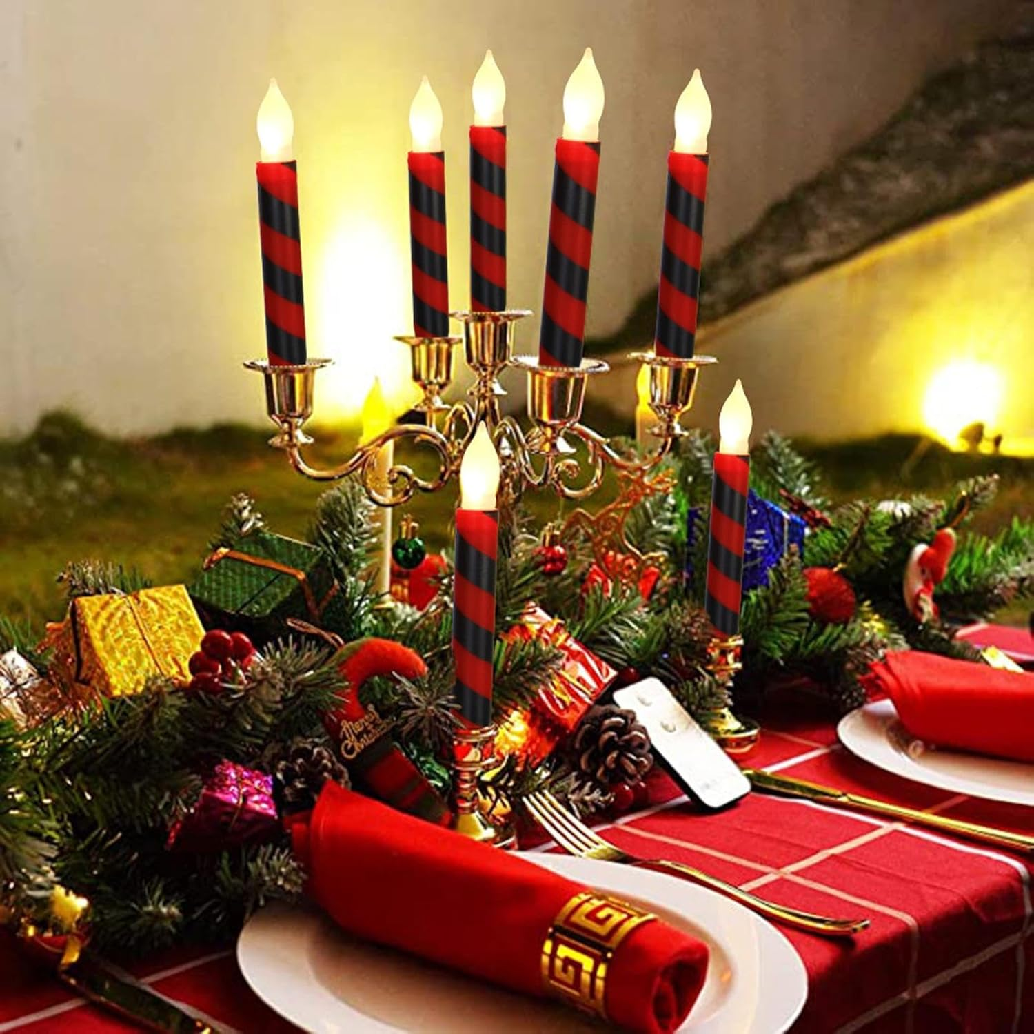 Weihnachtstisch mit Leuchter, rot-schwarzen Kerzen, roten Servietten und festlichen Dekorationen auf roter Tischdecke.