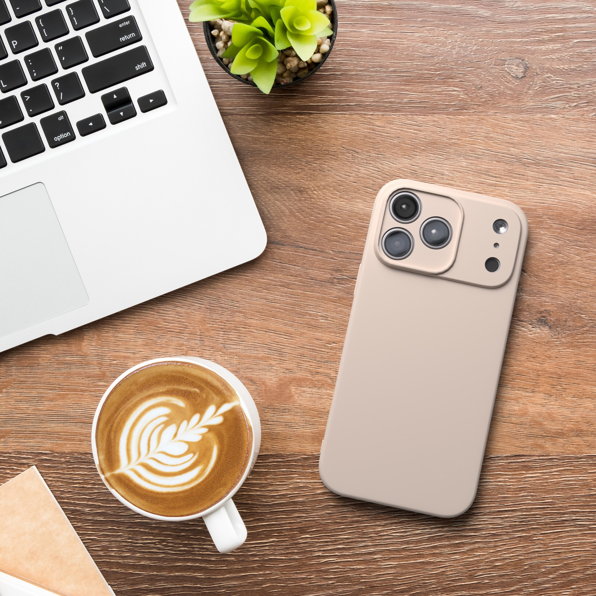 Ein Laptop, Kaffee mit Latte Art, Telefon und eine kleine Pflanze auf einem Holzschreibtisch. Draufsicht.