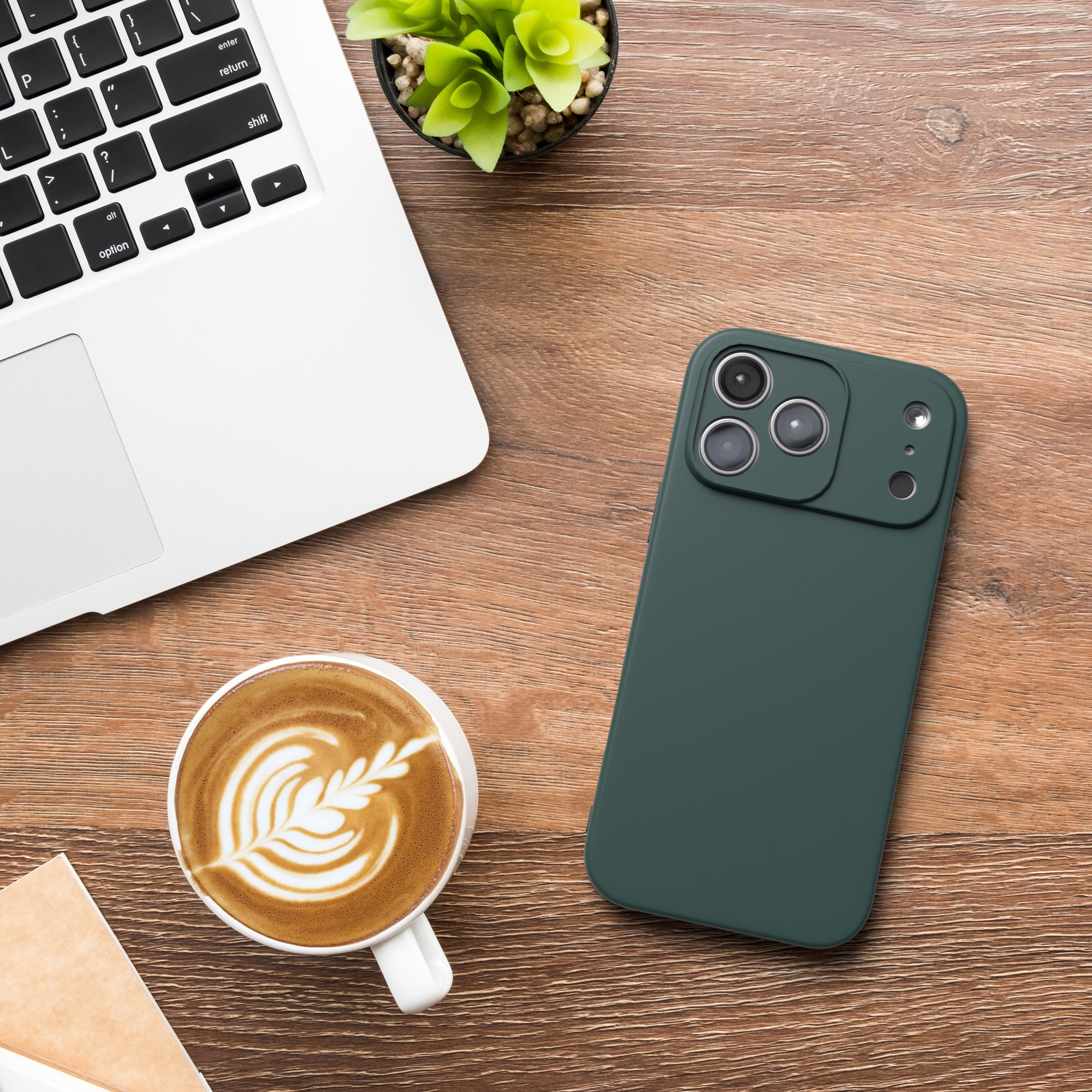Laptop, Telefon, Kaffee und Pflanze liegen auf Holz. Das Telefon ist grün. Kaffee hat Latte Art.