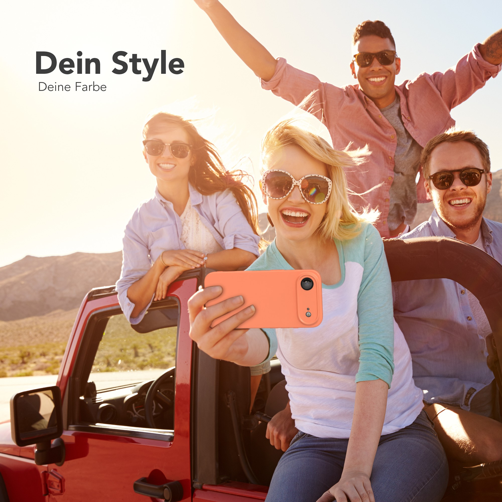 Freunde machen ein Selfie in einem roten Jeep. Einer hält das Telefon, andere lächeln und posieren vor sonnigem Hintergrund.