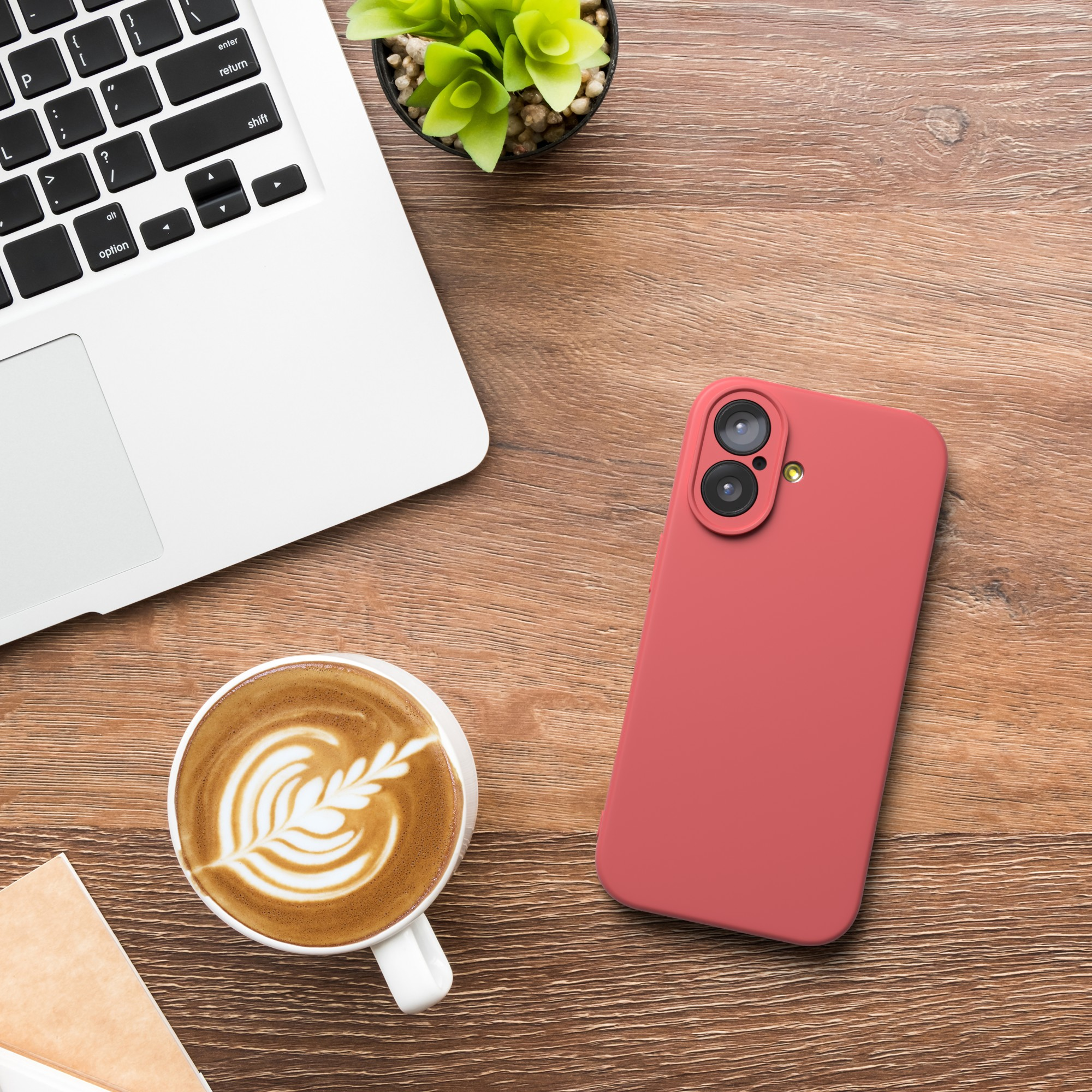 Ein Laptop, eine Kaffeetasse mit Latte Art, ein rotes Telefon und eine kleine Pflanze stehen auf einem Holztisch.