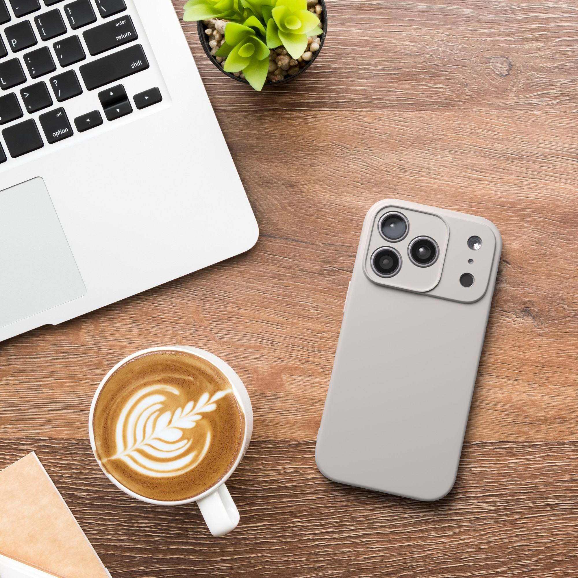 Draufsicht: Laptop, Telefon, Kaffee und Pflanze auf Holztisch. Telefon hat drei Kameras.