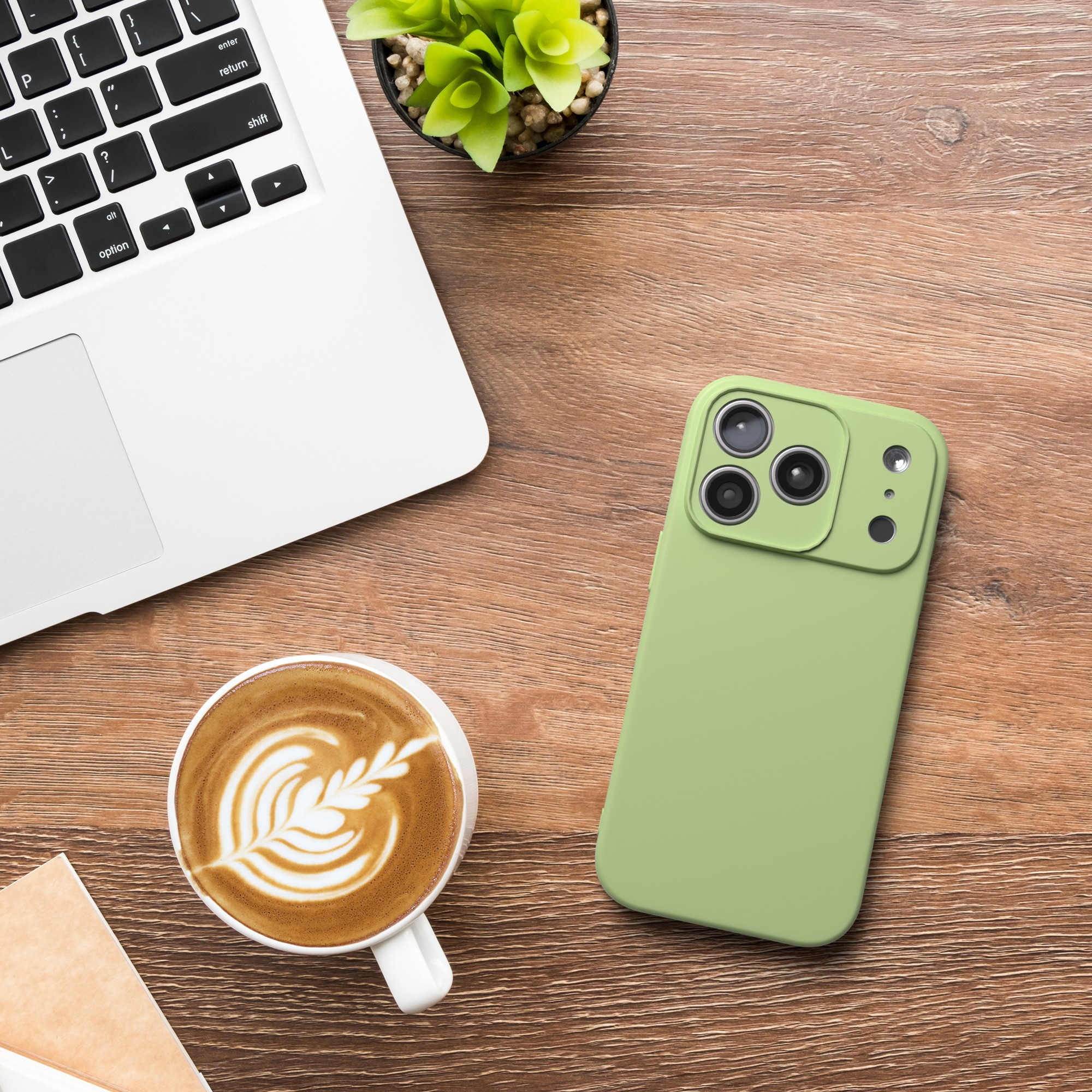 Ein Laptop, Kaffee mit Latte Art, grünes Telefon und eine kleine Pflanze auf einem Holzschreibtisch.