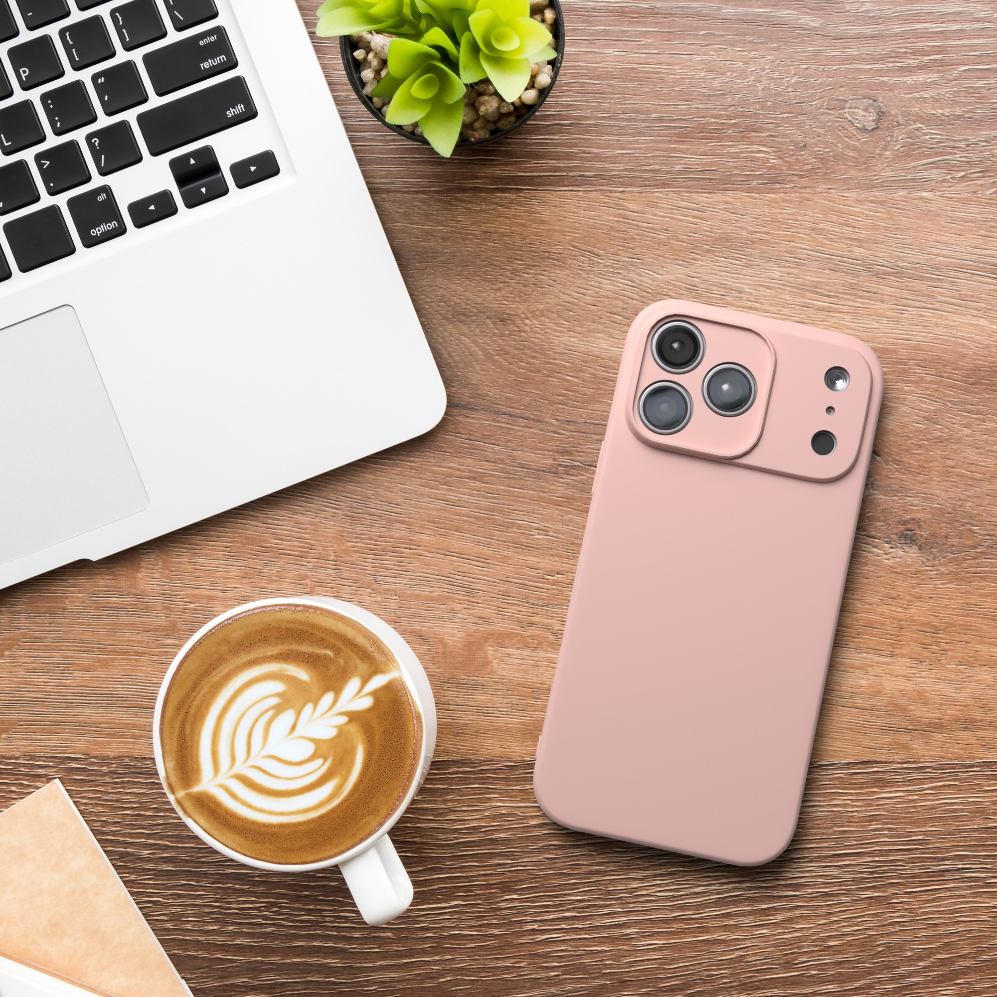 Ein Laptop, eine Kaffeetasse mit Latte Art und eine Handyhülle auf einer Holzoberfläche.