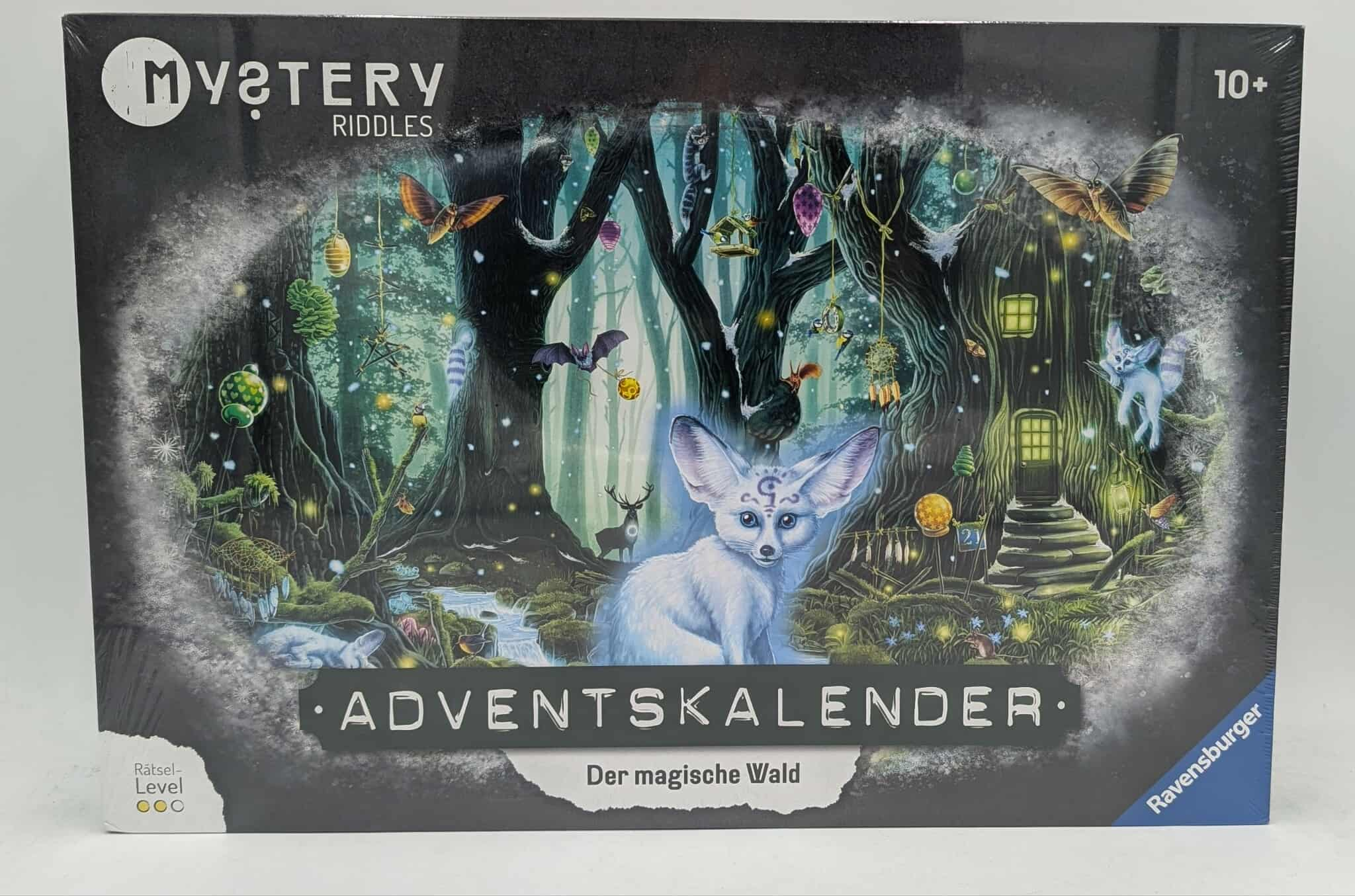 Eine Spielbox mit einer Fantasy-Waldszene mit einem weißen Fuchs, Bäumen und mystischen Kreaturen. Der Titel lautet 'Mystery Riddles'.