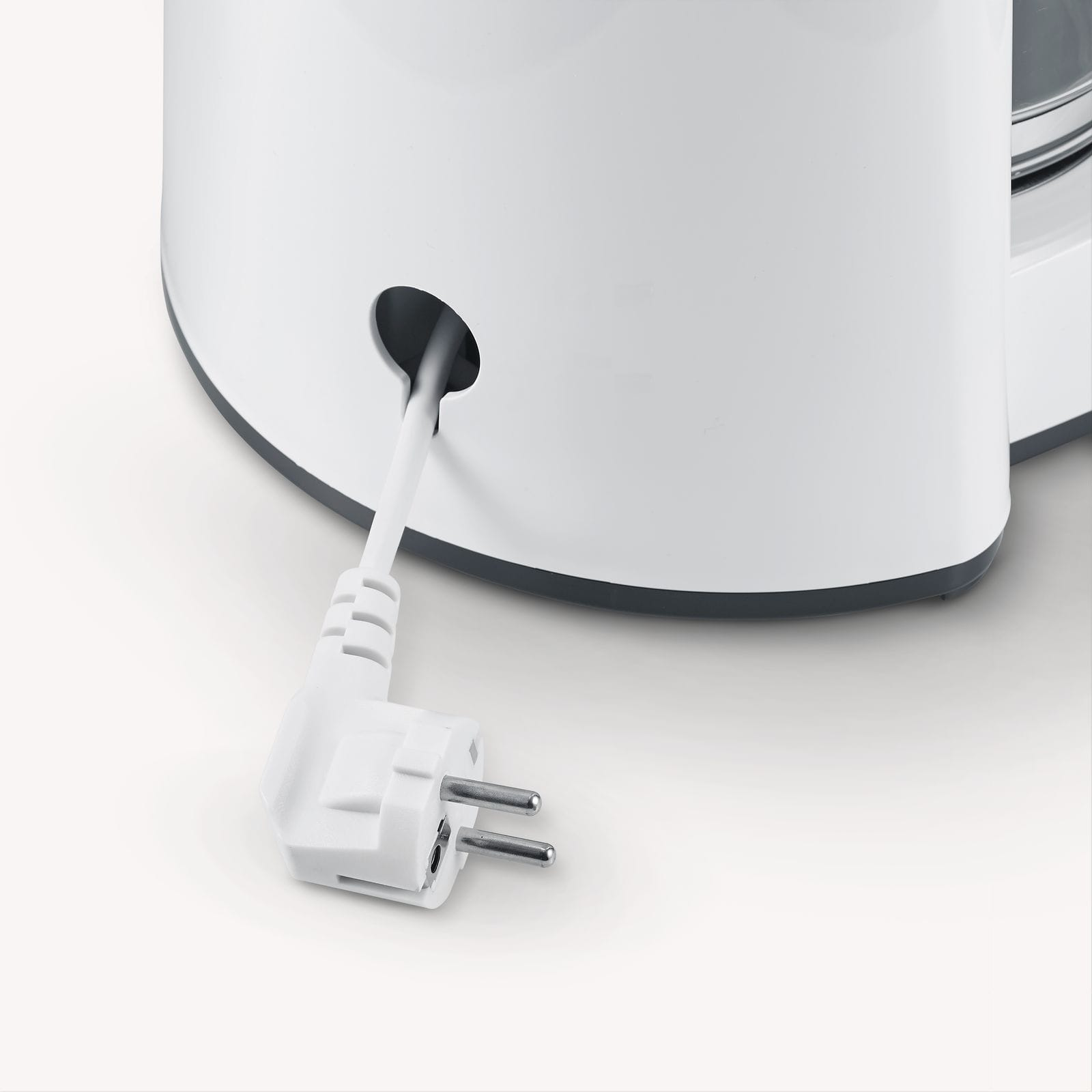 Białe urządzenie z przewodem zasilającym i wtyczką. Przewód wychodzi z otworu w urządzeniu.