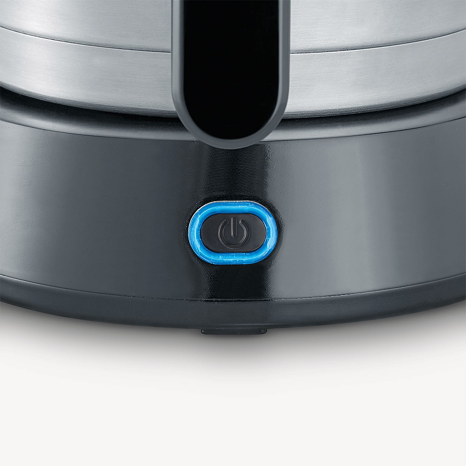 Zbliżenie na czarną podstawę czajnika elektrycznego z podświetlanym na niebiesko przyciskiem zasilania. Czajnik wykonany jest ze stali nierdzewnej.