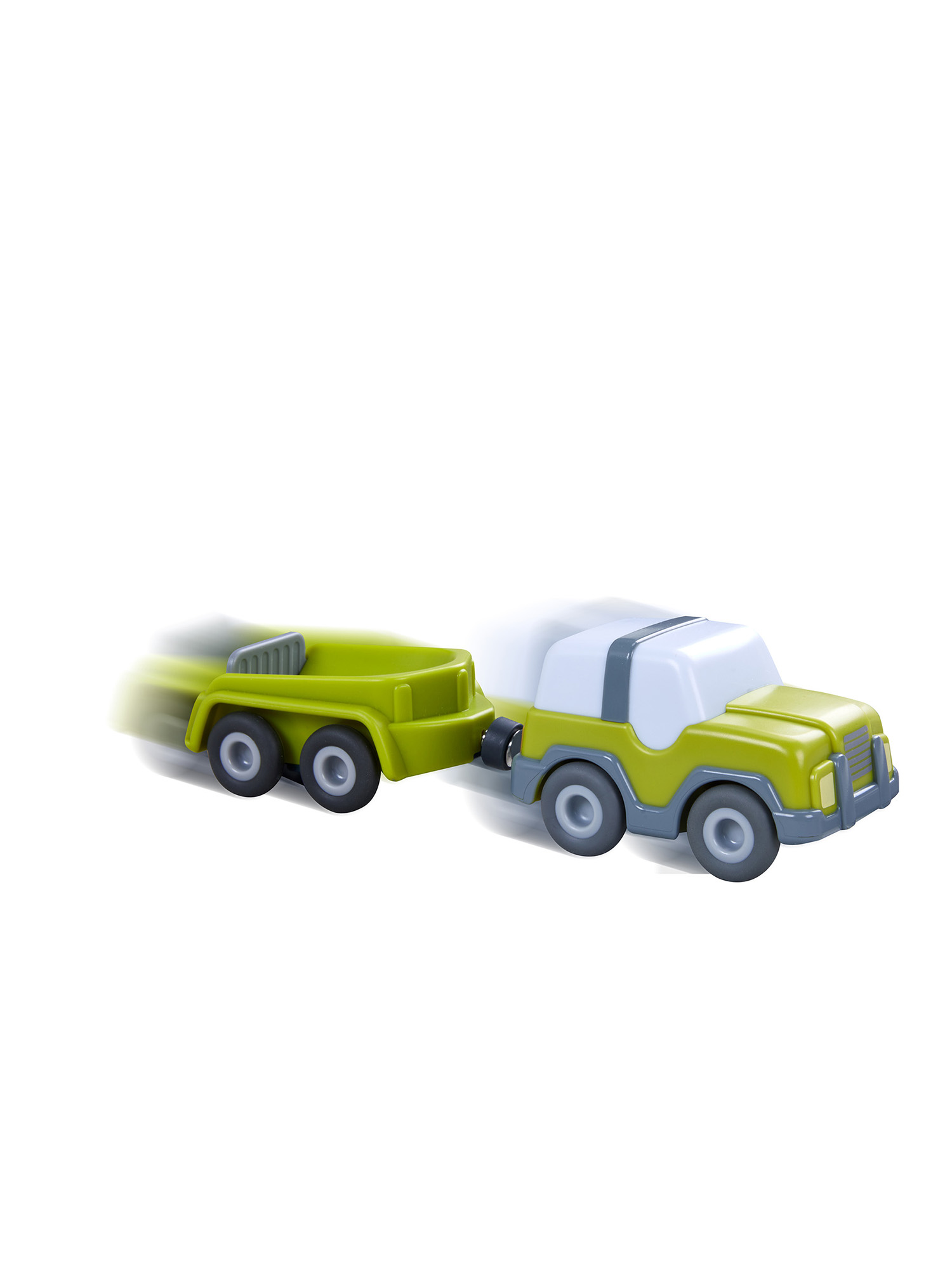 Zielona zabawka ciężarówka ciągnie zieloną przyczepę. Ciężarówka ma biały dach. Oba w ruchu, wskazane przez rozmycie ruchu.