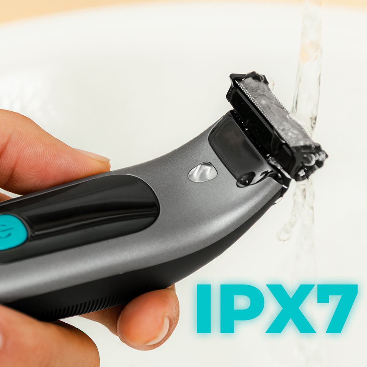 Eine Hand hält einen grauen und schwarzen Elektrorasierer unter fließendem Wasser. Der Text "IPX7" ist in Türkis sichtbar.