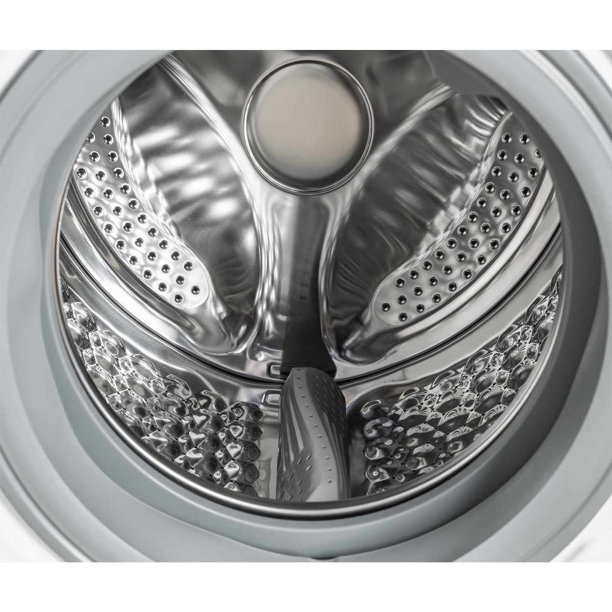 Dentro del tambor de una lavadora, metal brillante con perforaciones. Un agitador de plástico gris en la parte inferior. Un marco gris lo rodea.