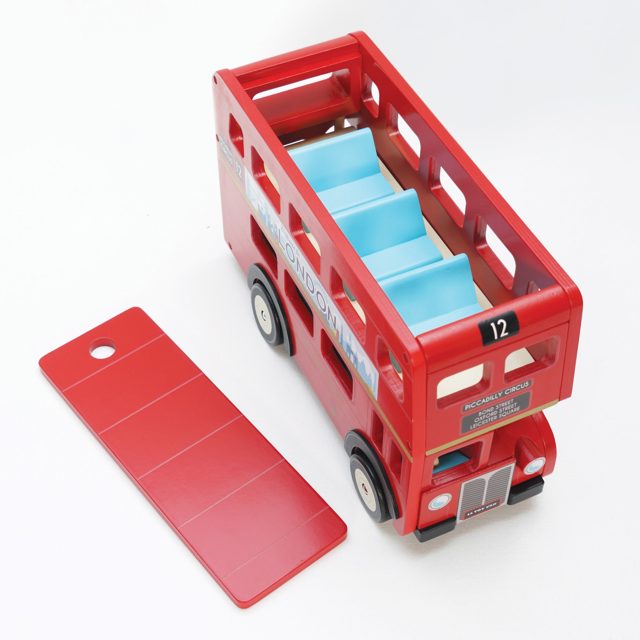 Ein rotes hölzernes Doppeldeckerbus-Spielzeug mit blauen Sitzen und einem roten, abgenommenen Teil auf weißer Oberfläche.