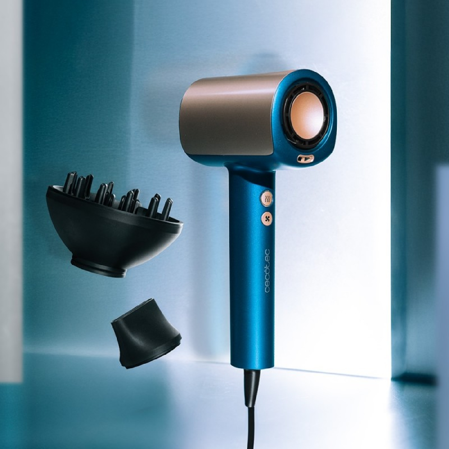Un asciugacapelli blu e argento con accessori. Un accessorio è un diffusore, l'altro un ugello. Lo sfondo è azzurro.