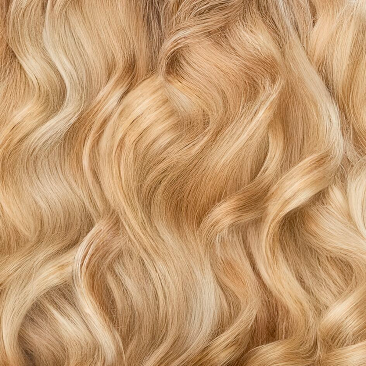 Close-up van golvend, lichtblond haar. Haarstrengen overlappen elkaar, met variaties in tint. De textuur lijkt zacht en vloeiend.
