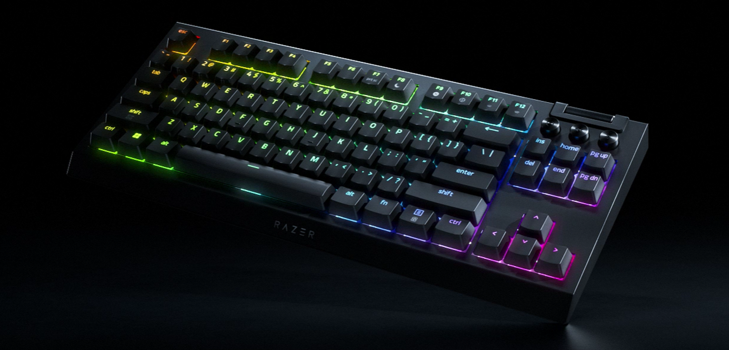 Tastiera Razer nera con tasti illuminati multicolore su una superficie nera. I tasti sono etichettati.