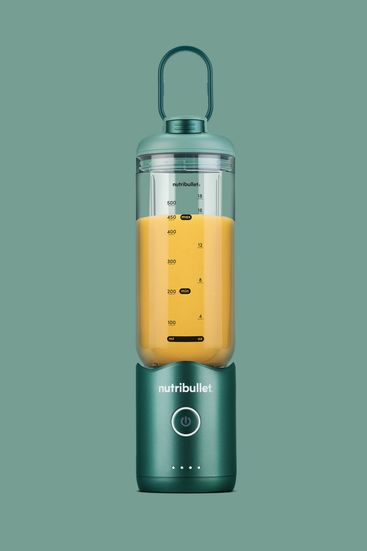Un frullatore Nutribullet verde con liquido arancione all'interno. Ha un manico. Lo sfondo è di un colore verde abbinato.