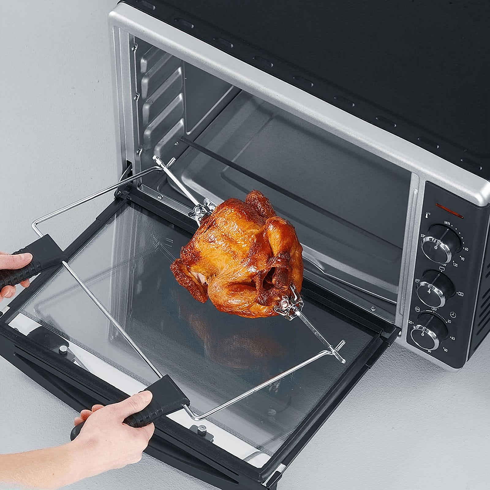 Pollo asado en horno, puerta abierta. Manos sujetan la puerta. Controles del horno visibles.