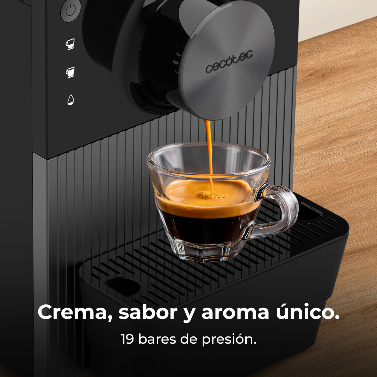 Una cafetera vierte espresso en una taza de vidrio. La máquina es negra y el fondo es una superficie de madera.
