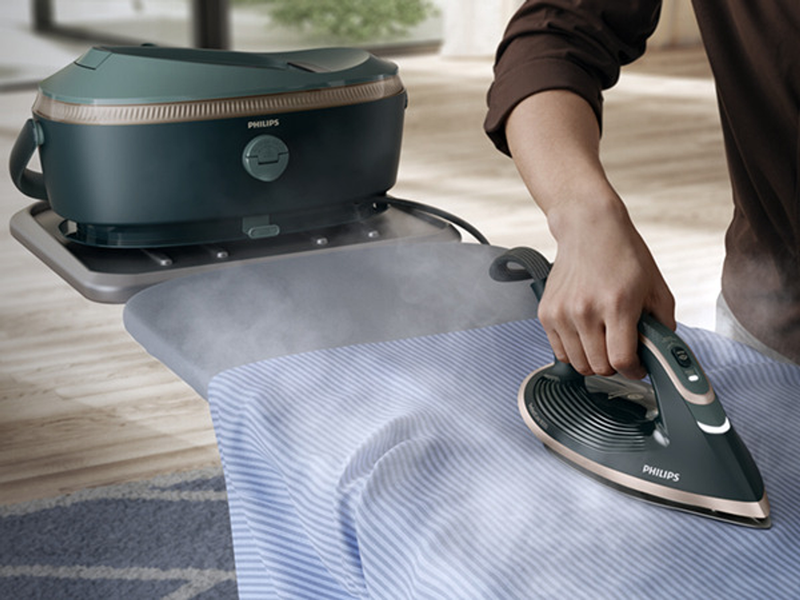Una persona planchando una camisa a rayas azules con una plancha Philips. Una plancha de vapor está a la izquierda.