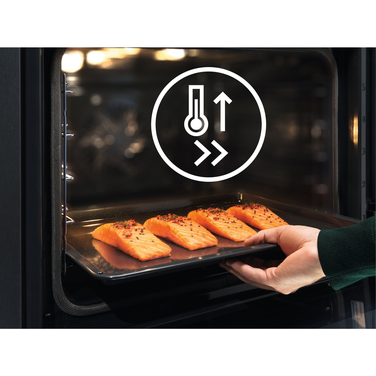 Una mano coloca una bandeja de filetes de salmón en un horno. El horno muestra un icono de temperatura. El salmón está sazonado.