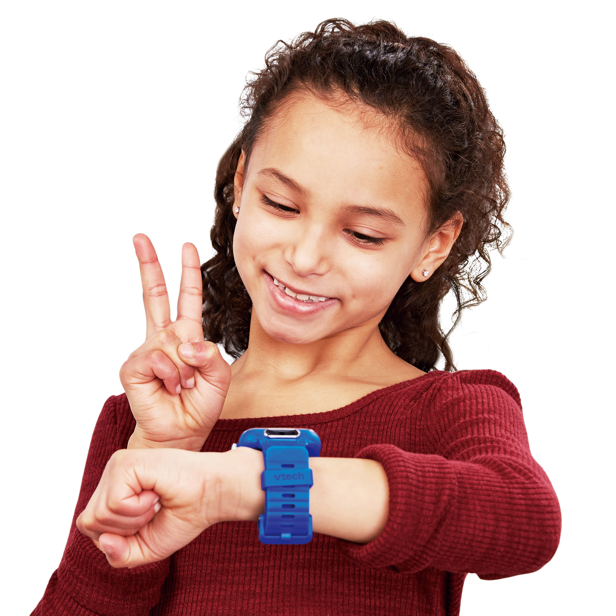 Una niña sonríe y levanta dos dedos. Lleva una camisa roja y un reloj inteligente azul en la muñeca. Fondo blanco.