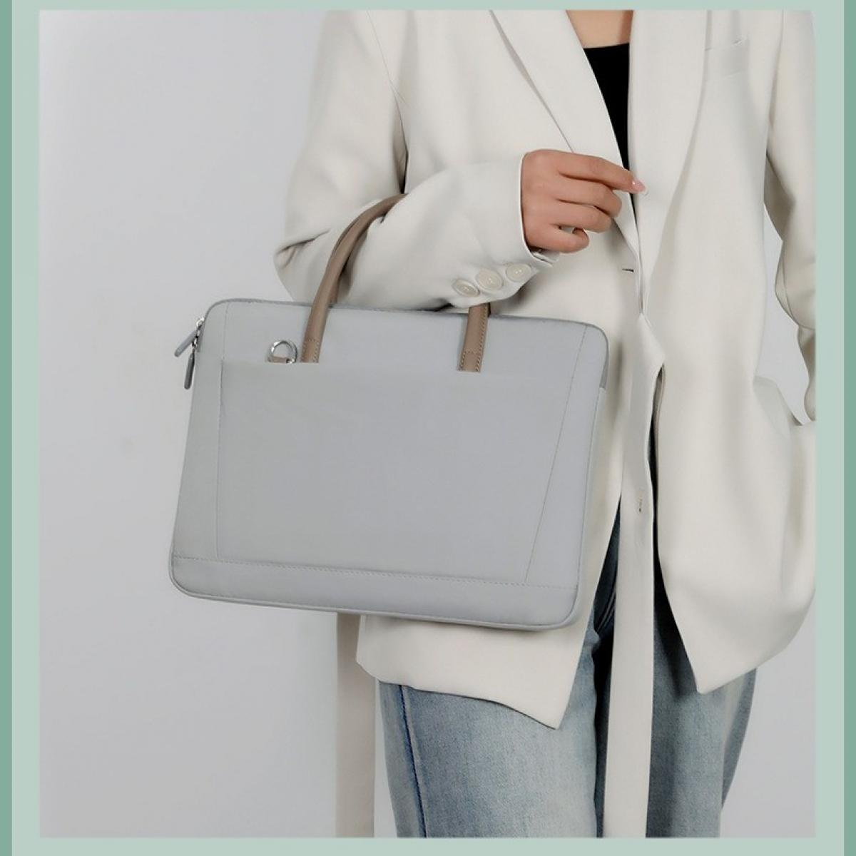 Eine Person in einem weißen Blazer hält eine hellgraue Laptoptasche mit braunen Griffen. Sie trägt Jeans. Der Hintergrund ist weiß.