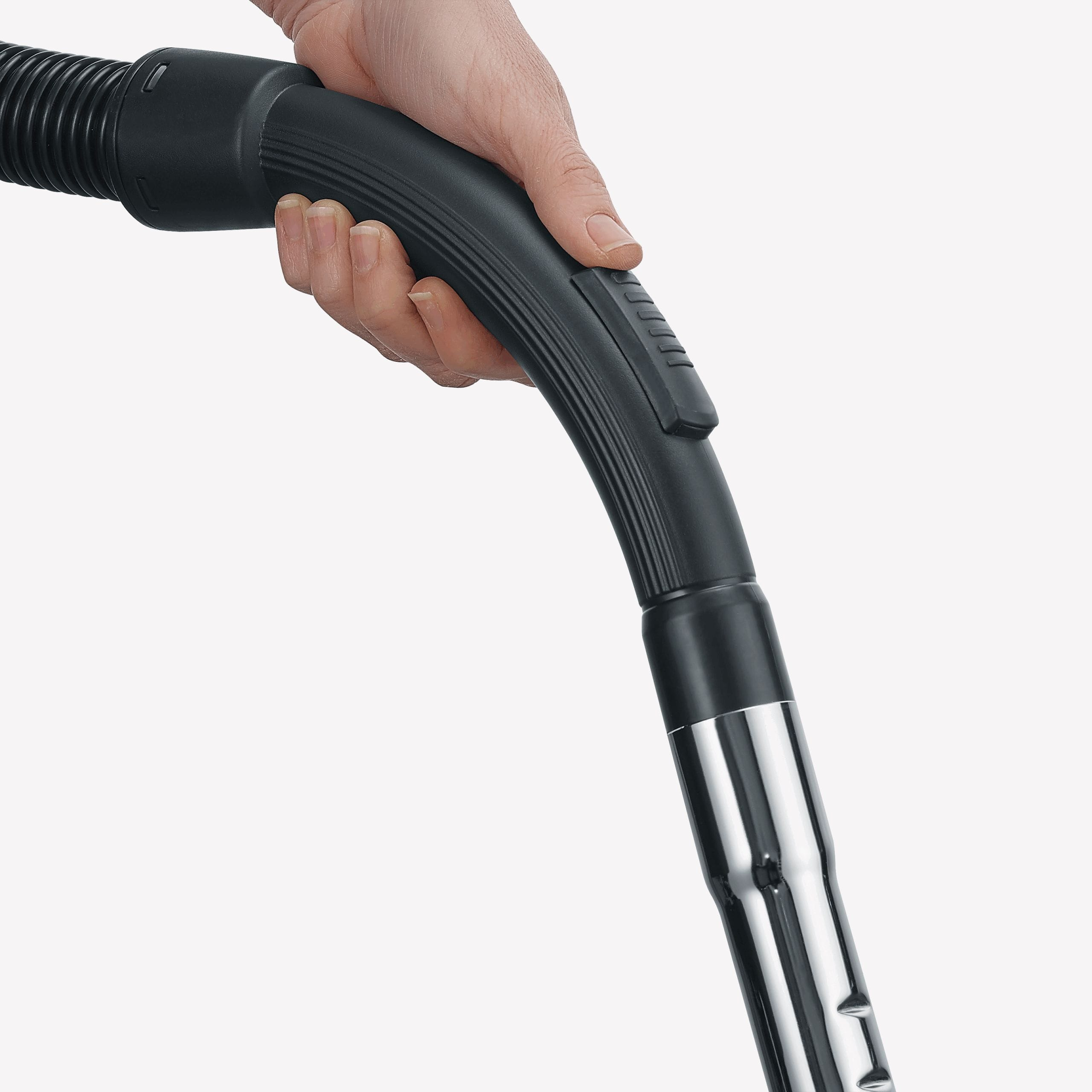 Ręka trzyma czarny uchwyt odkurzacza. Uchwyt zakrzywia się z chromowanym końcem.