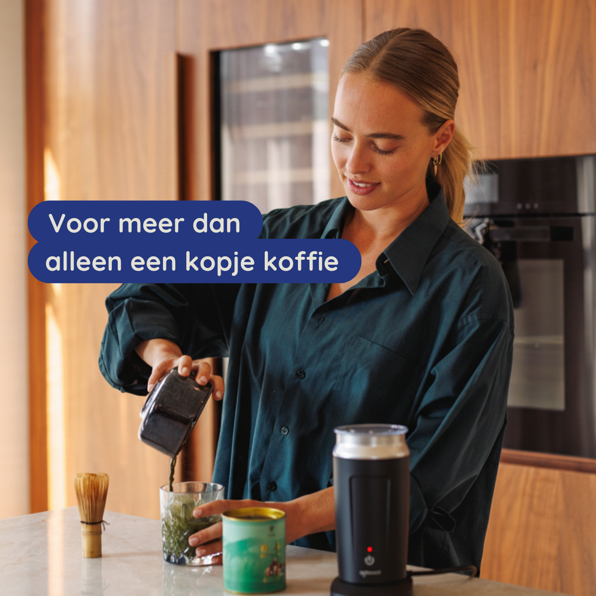 Vrouw giet een donkere vloeistof in een glas met groene inhoud. Een garde, een blikje en een opschuimer staan op het aanrecht. Tekst overlay.