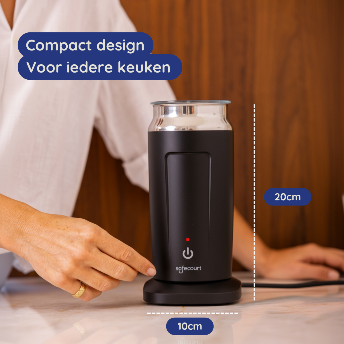 Een zwart en zilver SafeCourt-apparaat staat op een aanrecht. Een vrouwenhand is in de buurt. Tekst: 'Compact design, Voor elke keuken'.