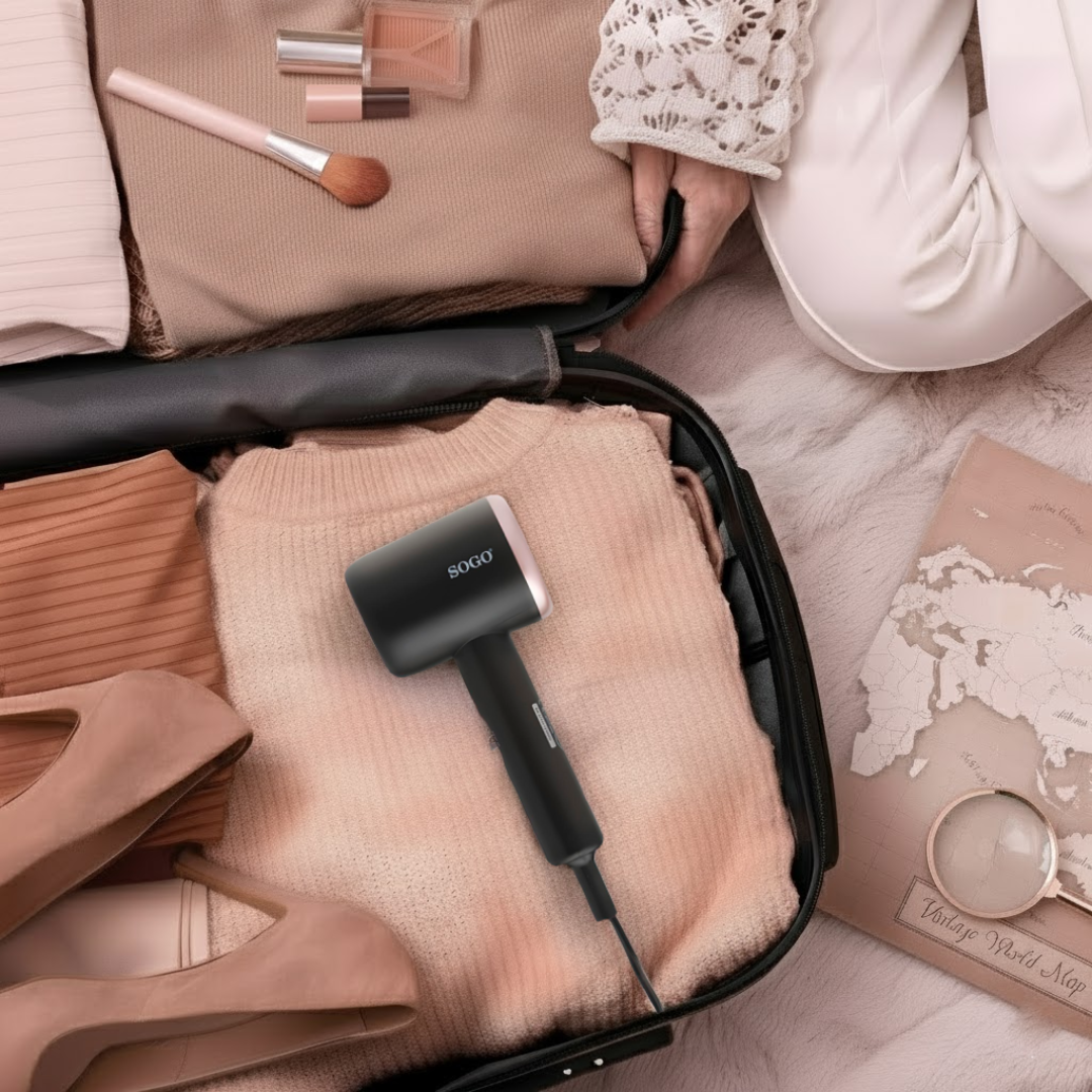 Una maleta abierta, llena de ropa y productos de belleza. Una plancha de vapor SOGO negra descansa sobre un suéter melocotón. Un mapa y una lupa están cerca.