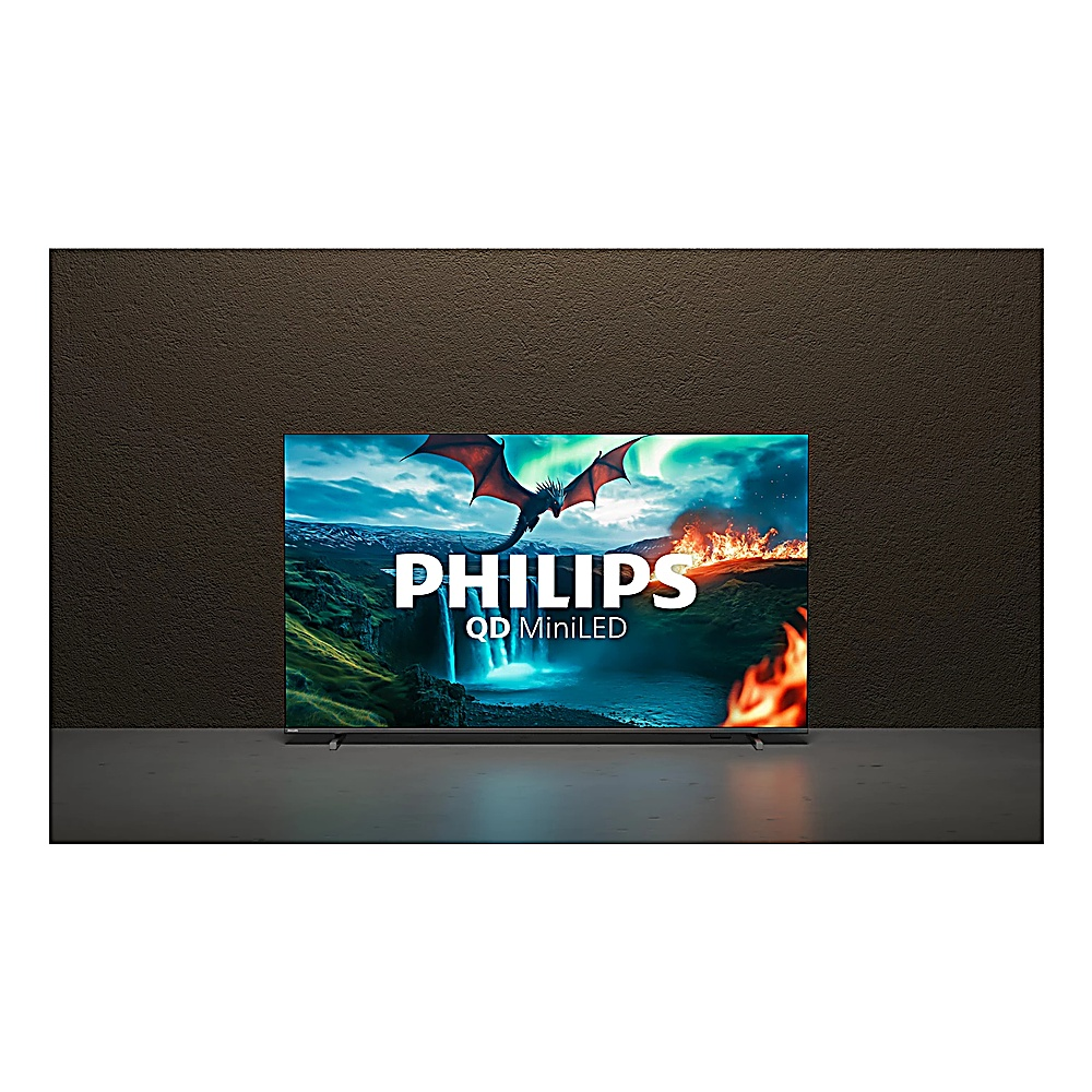 Bir Philips QD MiniLED TV, bir ejderha, şelale ve ateş içeren bir fantezi sahnesi sergiliyor. TV, kahverengi bir duvarın önünde gri bir yüzey üzerinde duruyor.