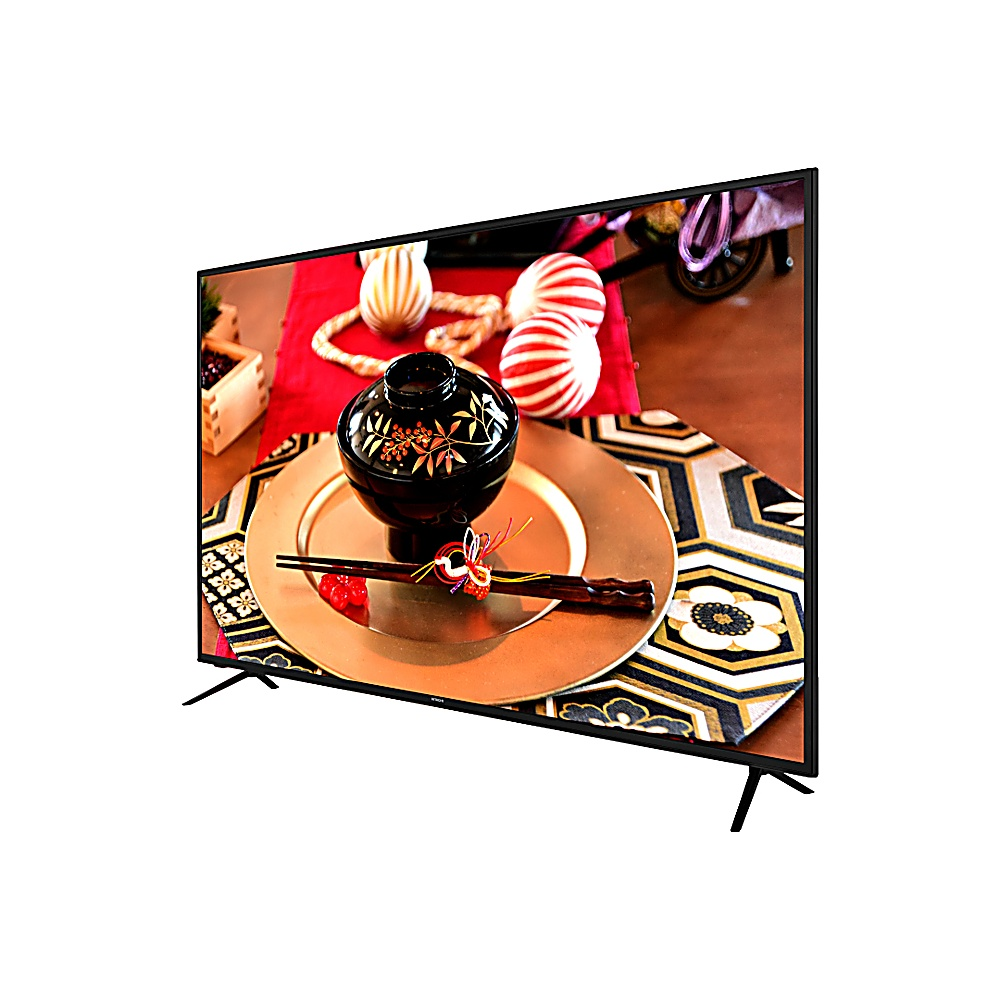 Un televisor muestra una comida japonesa. Cuenco negro sobre plato dorado con palillos. Decoraciones rojas y blancas. Caja de madera al fondo.