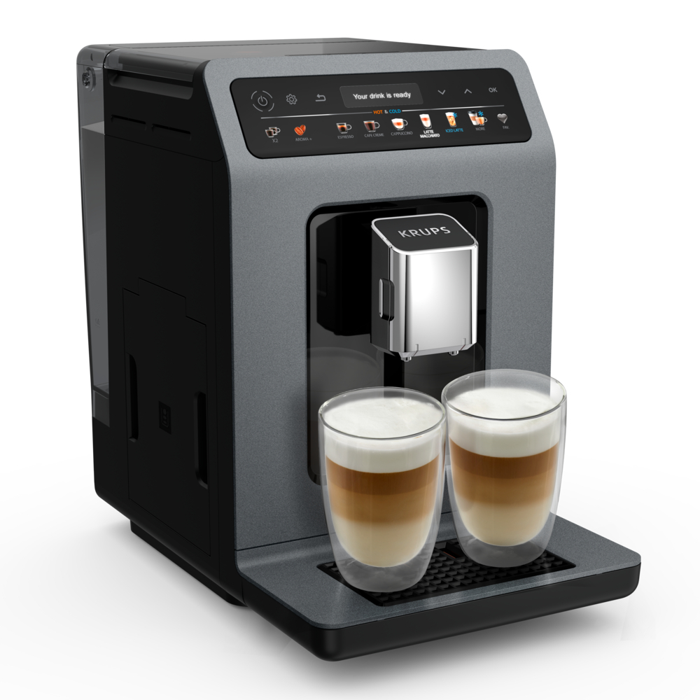 Una macchina da caffè con due bicchieri di latte macchiato. La macchina è grigia e nera con display digitale. Il marchio è KRUPS.