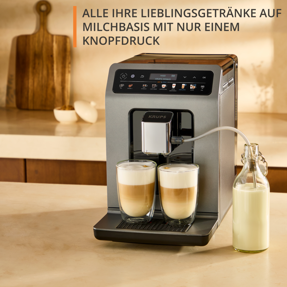 Una macchina da caffè con due bicchieri di latte macchiato. Una bottiglia di latte a destra. La macchina è grigia.