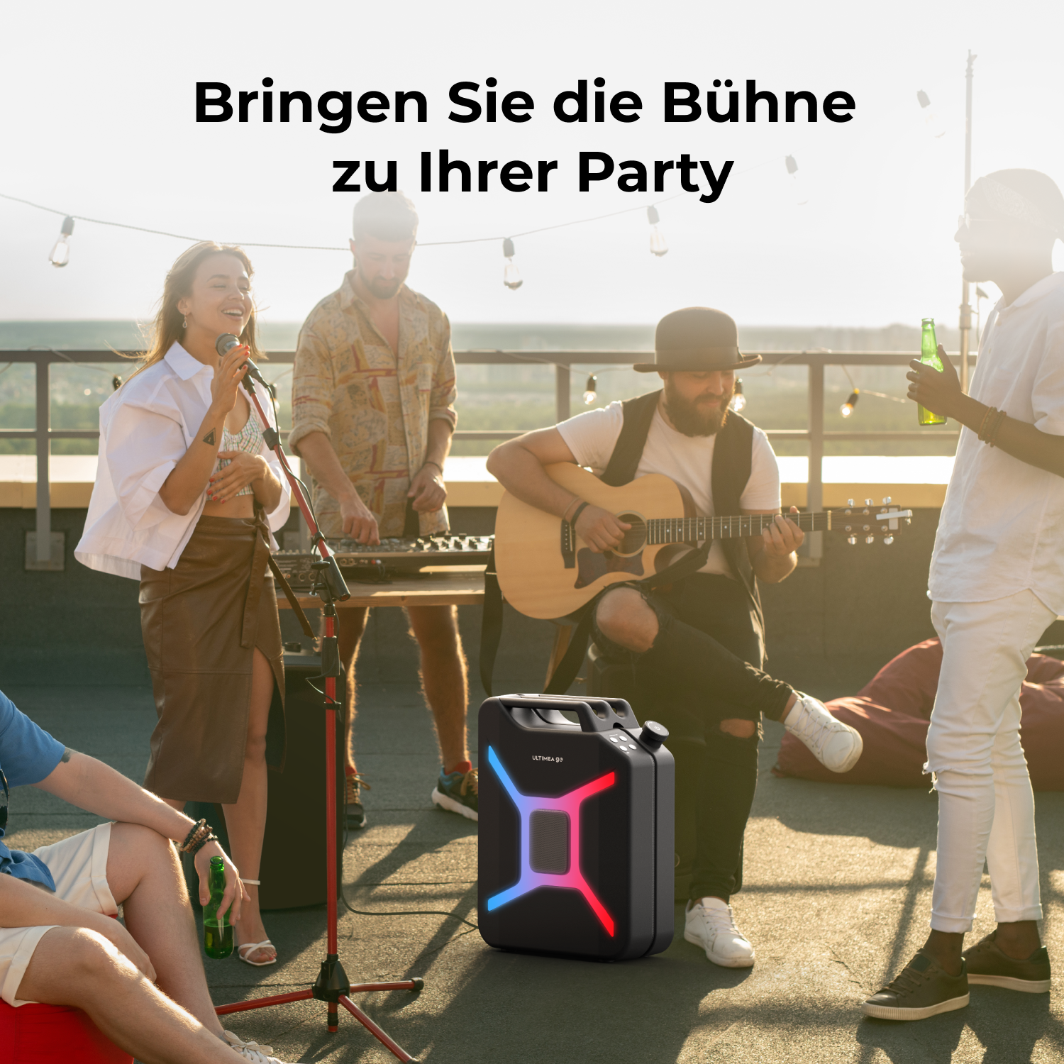 Eine Band spielt auf einem Dach. Ein Lautsprecher mit bunten Lichtern steht im Vordergrund. Leute singen, spielen Gitarre und genießen Getränke.